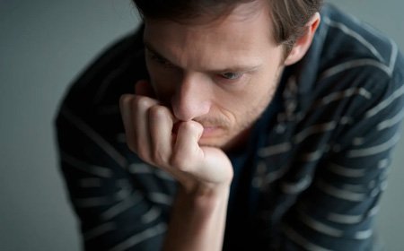 Мужчина сидит положив подбородок на руку